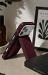 Wine red phone wallet in stand mode beside books, candle