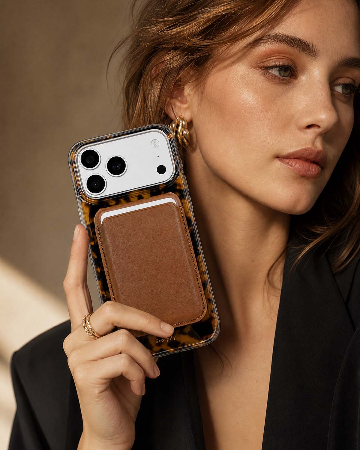 Woman in black blazer holding classic brown phone wallet