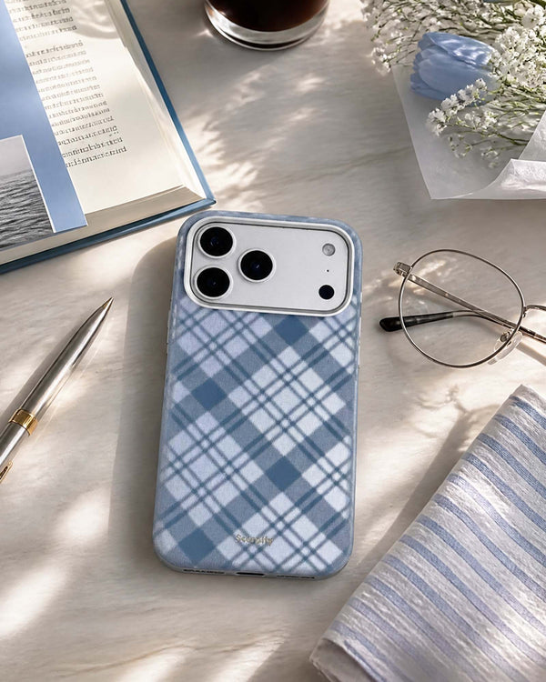 Navy tartan leather phone case on desk with glasses and pen