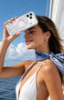 Woman holding clear silver shell phone case outdoors