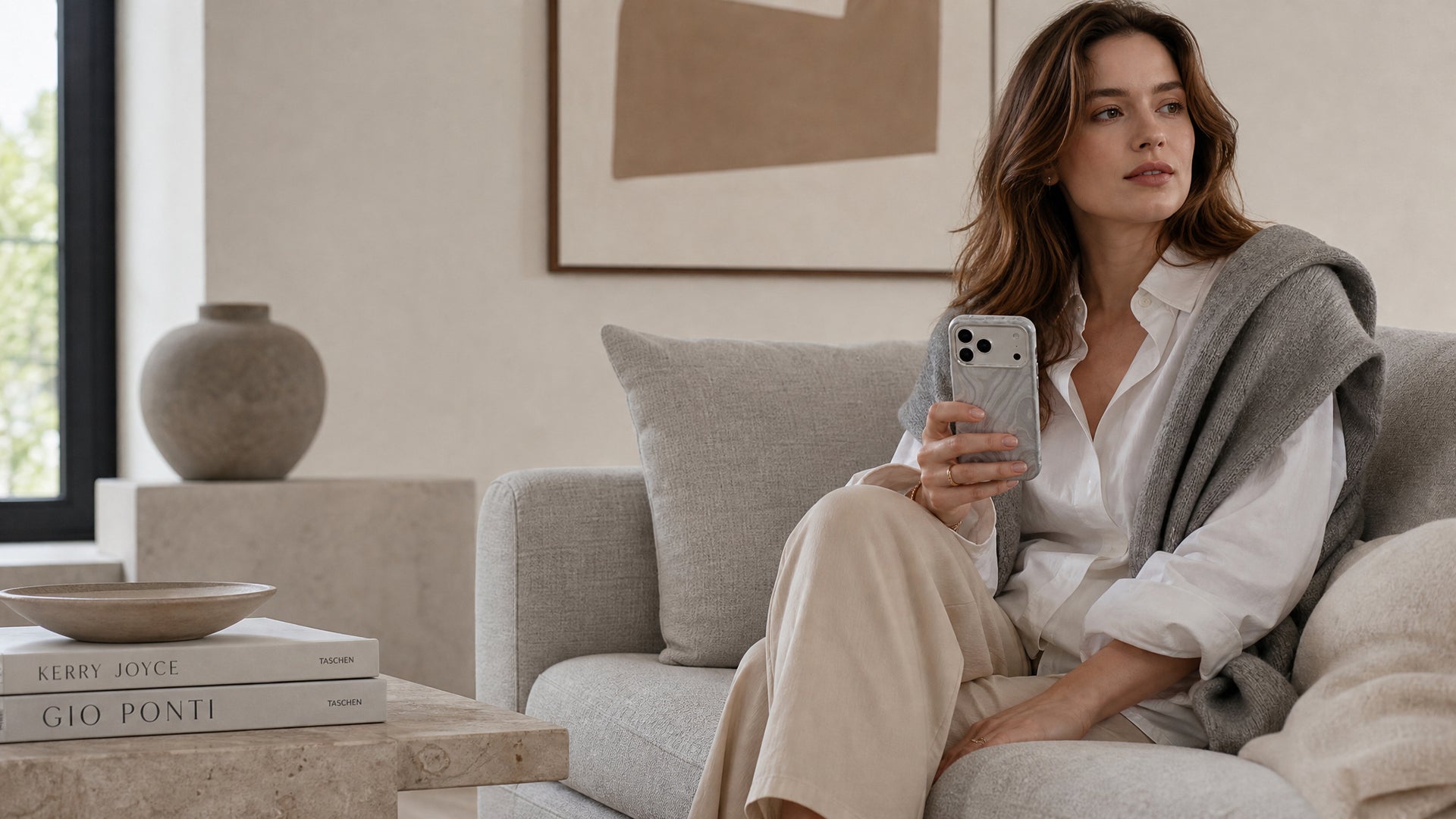 Woman on sofa holding silver swirl leather phone case