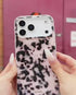 Pink tortoise shell iPhone case held outdoors